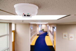 A fire alarm detector on the ceiling in a commercial building.